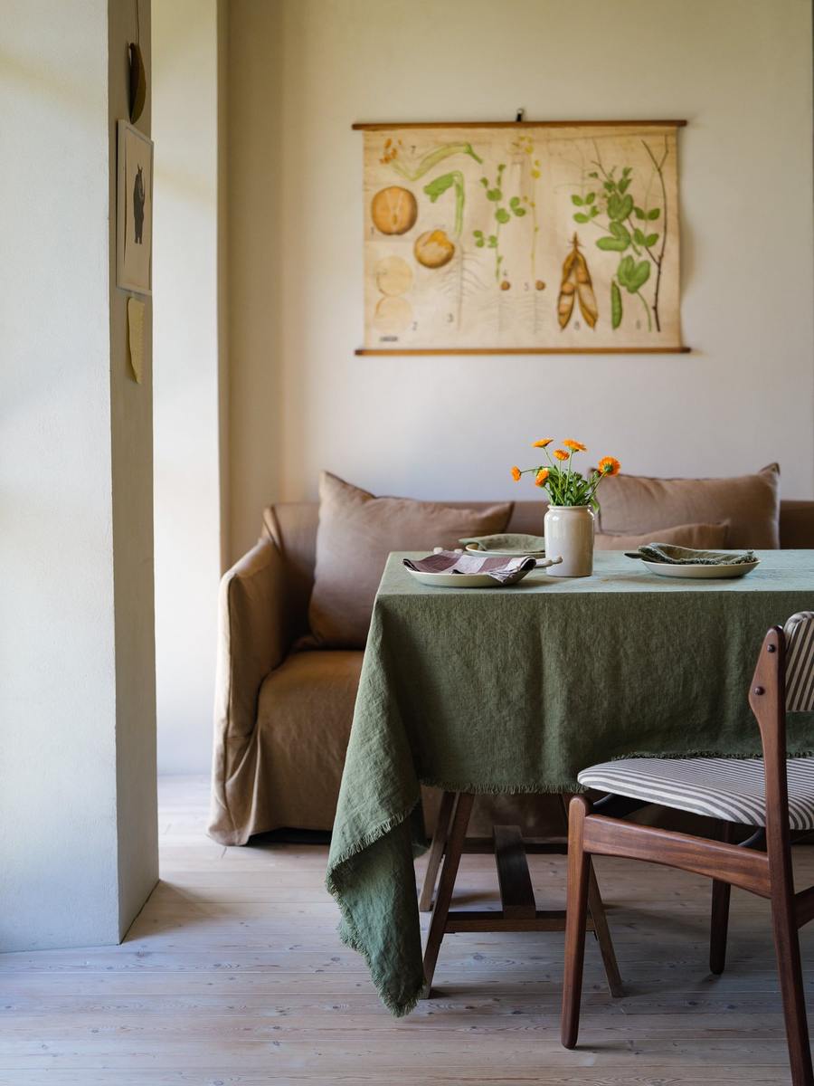 Mantel Olive Green Terra Fringe con platos crema y flores naranjas