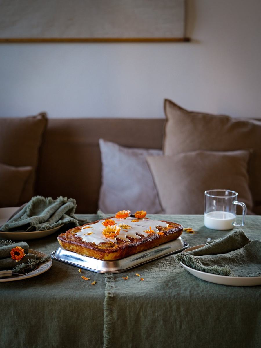 Pastel con flores naranjas sobre lino verde oliva y servilletas con flecos
