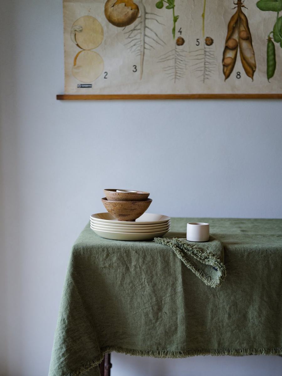 Platos crema y cuencos de madera sobre lino verde oliva