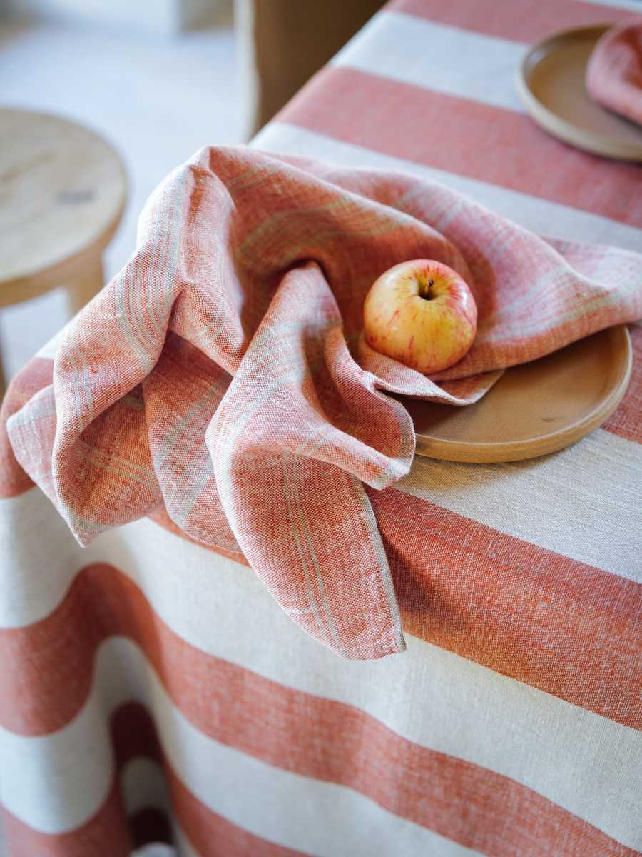 Servilleta de lino a rayas ladrillo con una manzana sobre un plato beige