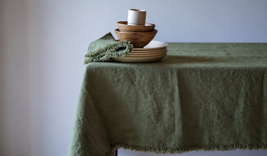 Mantel y servilleta Olive Green Terra Fringe con platos crema y cuencos de madera