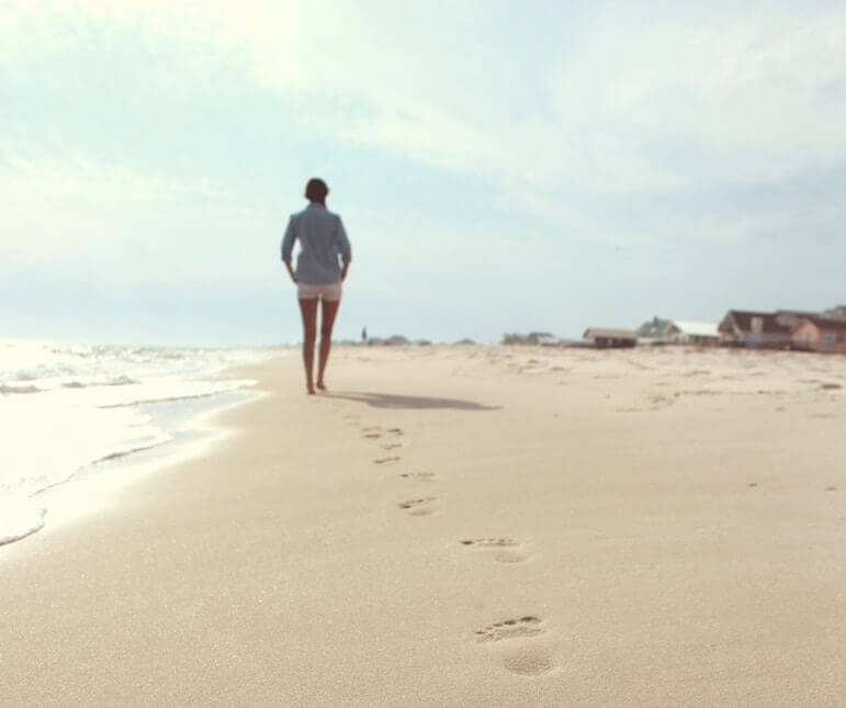 Persona caminando por una playa de arena con ropa ligera