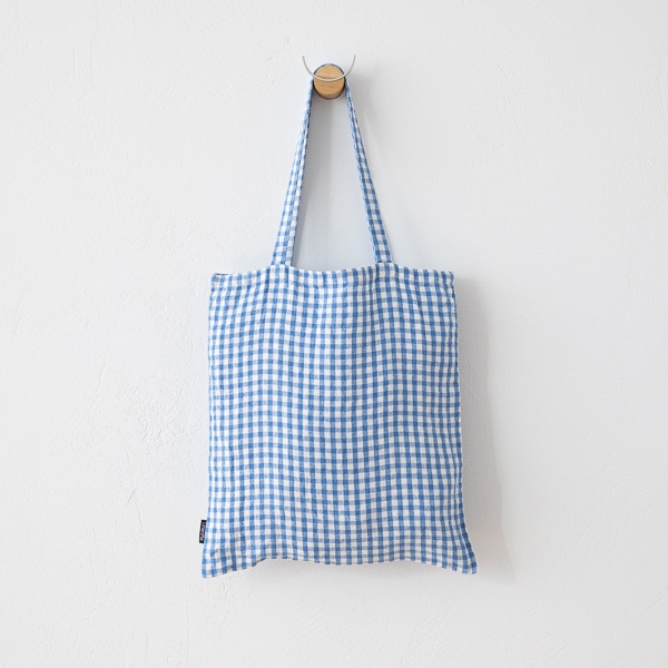 Bolso tote de lino a cuadros vichy azules colgado de frente en un gancho de pared