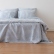 Ropa de cama de lino Blue Ticking Stripe cayendo por el lateral de una cama