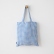 Bolso tote de lino a cuadros vichy azules colgado de frente en un gancho de pared